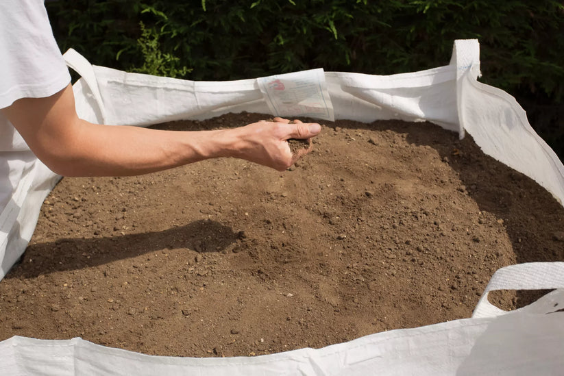 a person with a handful of topsoil from a ton bag after delivery